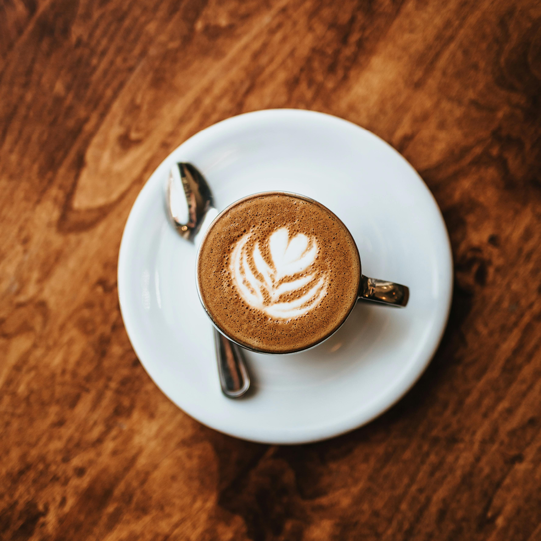 Ένας καφές με γάλα σε ξύλινο τραπέζι με latte art.