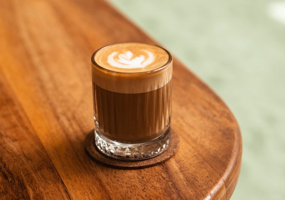 Ένα flat white στη γωνία του τραπεζιού.
